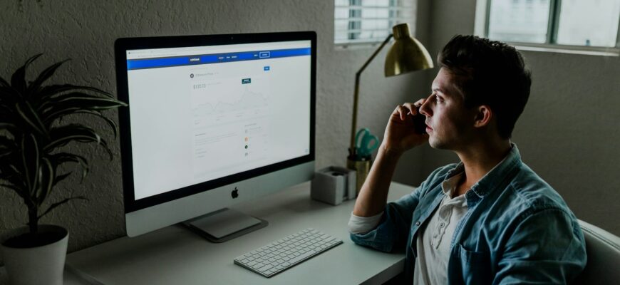 man in blue denim jacket facing turned on monitor