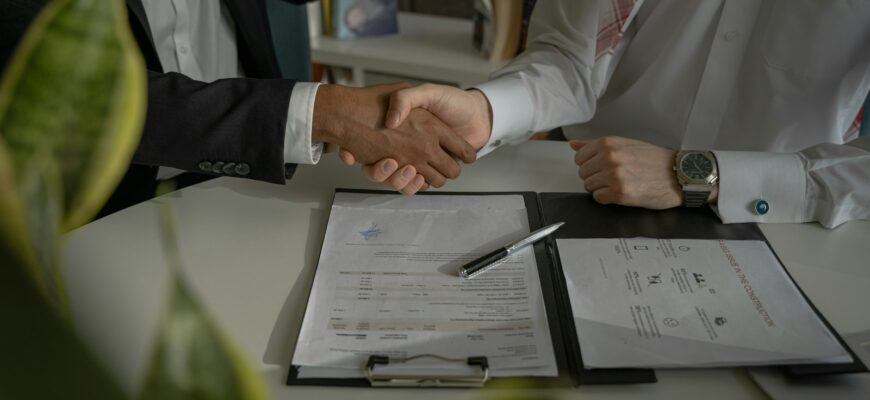 two people shaking hands over a piece of paper
