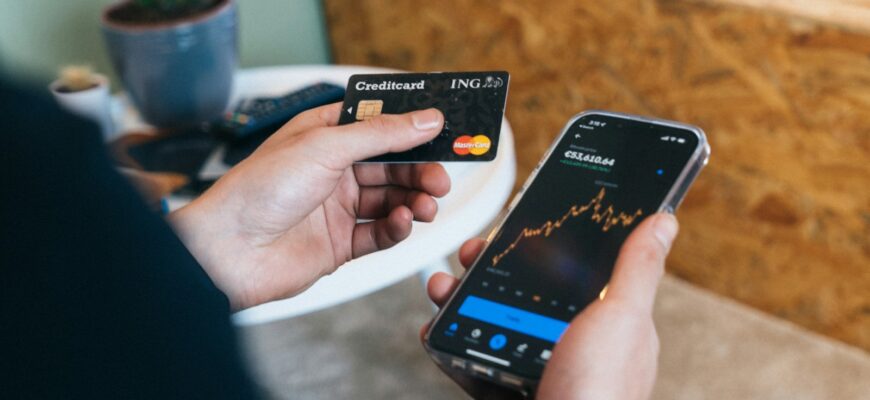 a person holding a smart phone and a credit card