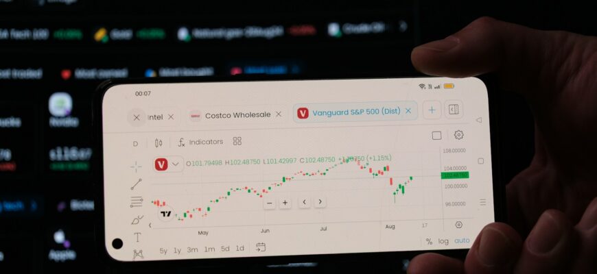 A person holding a business card in front of a computer screen