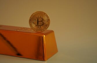Bitcoin coin resting on a gold bar.