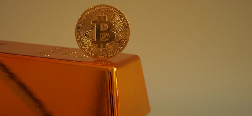 Bitcoin coin resting on a gold bar.